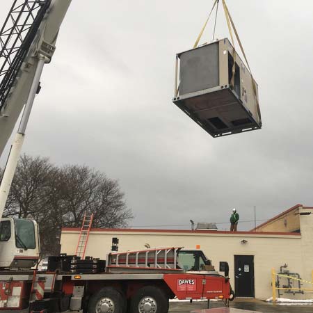 Crane lifting hvac unit onto roof