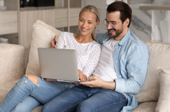 Couple On Couch Looking At Computer
